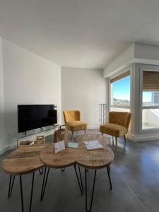 - un salon avec deux tables et des chaises ainsi qu'une télévision à écran plat dans l'établissement "Lou Mes" Baux-de-provence Balcon, aux Baux-de-Provence