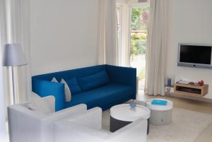 a living room with a blue couch and white chairs at Ostsee Lodges mit Wellnessbereich in Timmendorfer Strand