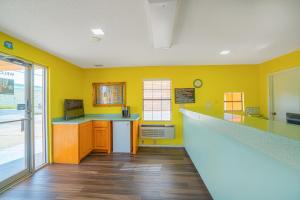 una cocina con paredes amarillas y una barra larga en Texas Inn San Benito near Harlingen, en San Benito