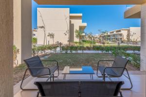2 chaises et une table sur une terrasse avec une cour dans l'établissement Modern 1-Bedroom Apartment in G-Cribs, El Gouna, pool access, à Hurghada