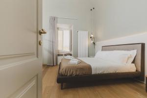 Schlafzimmer mit einem Bett mit weißer Bettwäsche und einem Spiegel in der Unterkunft Casa Horti Suites in LʼAquila