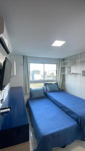 1 dormitorio con 2 camas azules y TV en Lindo Apartamento p/ 4 pessoas, a 60 m do mar, en João Pessoa