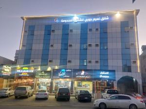 a large building with cars parked in a parking lot at نسيم جوري للشقق المخدومة Naseem Jouri Serviced Apartments in Taif