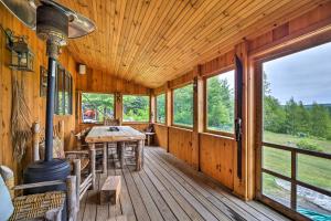 GreensboroにあるGreensboro Home with Porch and Countryside Views!の大きな木製ポーチ(テーブル、窓付)