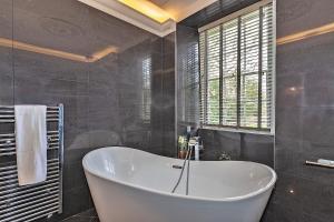 a bath tub in a bathroom with a window at Finest Retreats - Ttich Manor in Milton Keynes