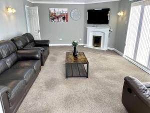 a living room with a leather couch and a fireplace at 5-Bedroom Cottage in Healing, Grimsby in Healing