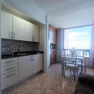 a kitchen with white cabinets and a table with chairs at Beachfront apartment Don Paco Patalavaca in Patalavaca