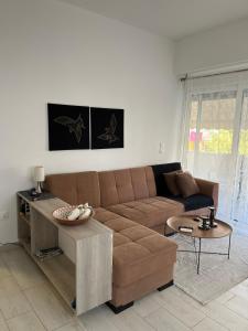 a living room with a brown couch and a table at Holiday Apartment Glyfada in Athens