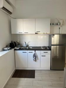 a kitchen with white cabinets and a stainless steel refrigerator at Holiday Apartment Glyfada in Athens