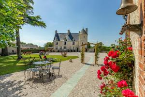 un jardín con mesas y sillas frente a un castillo en manoir de vauville, en Fresville