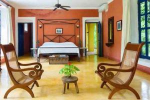 a bedroom with a bed and two rocking chairs at Hacienda extraordinaria, jardines preciosos y pirámides 
