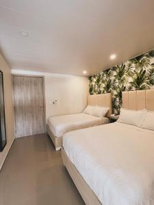 a bedroom with two beds and a wall with plants at Oasis Hotel in San Andrés
