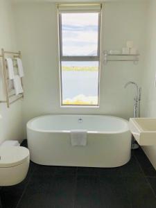 a white bathroom with a tub and a window at Spectacular Panoramic 5Bedroom Lakeview in Queenstown +20 photos