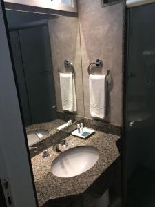 a bathroom with a sink and a mirror at San Diego Suítes Lourdes - OFICIAL in Belo Horizonte