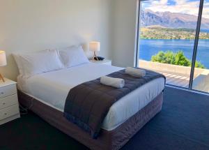 a bedroom with a large bed with a large window at Spectacular Panoramic 5Bedroom Lakeview in Queenstown