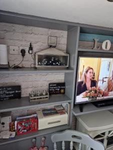 sala de estar con TV y estante en Fishermans Flint cottage, en Sheringham