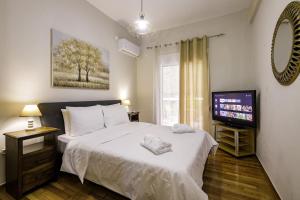 a bedroom with a white bed and a television at Fully renovated flat close to Uni & hospitals in Athens