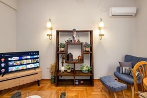 a living room with a television and a blue chair at Fully renovated flat close to Uni & hospitals in Athens