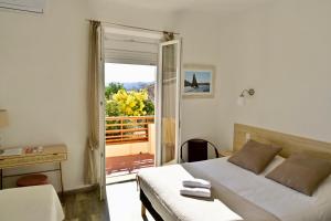 - une chambre avec un lit et une porte donnant sur un balcon dans l'établissement Hôtel La Petite Bohème, au Lavandou