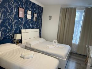 Duas camas num quarto com papel de parede azul e branco em Diana Hotel em Londres
