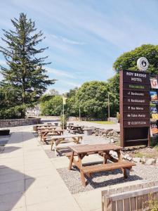 a row of picnic tables and a sign in a park at Roy Bridge Hotel in Fort William
