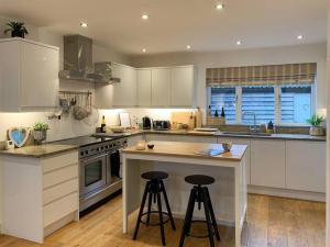 a kitchen with white cabinets and a island with bar stools at South Downs View in West Meon