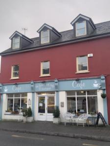 um edifício vermelho com cadeiras em frente em Mariners Rest One Bedroom Apartment in Innishannon Village em Cork