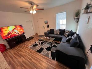 a living room with a black couch and a flat screen tv at The Heart Of Cruces in Las Cruces