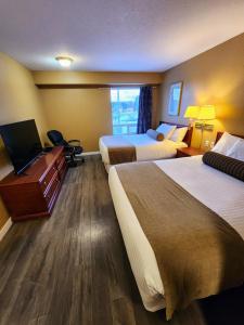 Pokój hotelowy z 2 łóżkami i biurkiem w obiekcie Fox Creek Inn w mieście Fox Creek