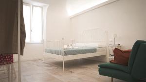 ein weißes Schlafzimmer mit einem Bett und einem Stuhl in der Unterkunft Corso Italia Pisa Smart Rooms in Pisa