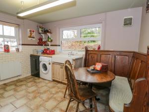 - une cuisine avec une table et un lave-linge dans l'établissement Bodorwel Cottage, à Penrhyndeudreath