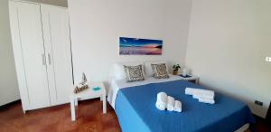 Schlafzimmer mit einem Bett mit blauer Bettwäsche und einem Tisch in der Unterkunft Limoncello Home con Veranda vista Mare a 3 Min dalla spiaggia in Alcamo