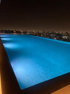 een blauw zwembad 's nachts met een stad bij Exquisite Apt @ Lennox Airport. in Accra