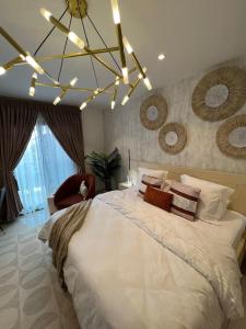 una camera da letto con un grande letto bianco e un lampadario a braccio di Exquisite Apt @ Lennox Airport. a Accra