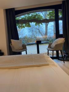 een slaapkamer met een bed en een groot raam bij Chambres d'hôtes Eucalyptus et Glycine in Genval