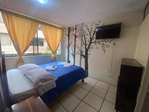 a bedroom with a blue bed and a tv at Hostal los Andes in Baños