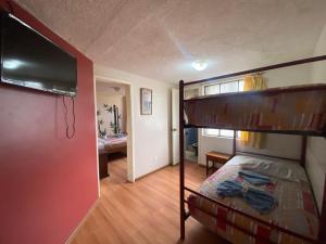 a bedroom with a bunk bed with a flat screen tv at Hostal los Andes in Baños