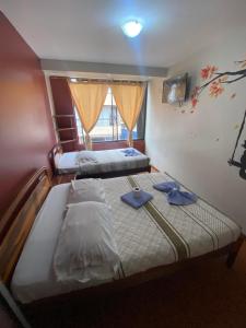 twee bedden in een kamer met twee blauwe slippers bij Hostal los Andes in Baños
