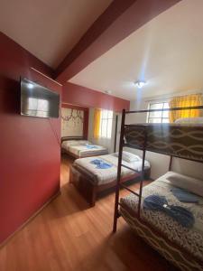 a bedroom with two bunk beds and a flat screen tv at Hostal los Andes in Baños