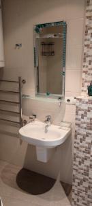 ein Badezimmer mit einem weißen Waschbecken und einem Spiegel in der Unterkunft Apartment Orbi Plaza in Batumi