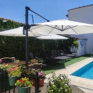 een patio met tafels en parasols naast een zwembad bij Casa Capricho del Destino 
