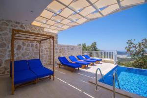 patio z niebieskimi krzesłami i basenem w obiekcie Villa Karmen w Kaş