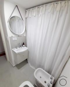 y baño con cortina de ducha blanca y aseo. en Mono Neuquen en Neuquén