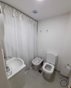 a white bathroom with a toilet and a sink at Mono Neuquen in Neuquén