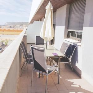 a balcony with a table and chairs and an umbrella at APTO PLAYA DEL CARMEN INVERDRABA in Barbate