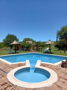 una gran piscina con un patio de ladrillo en Roena Cabañas en Villa Giardino