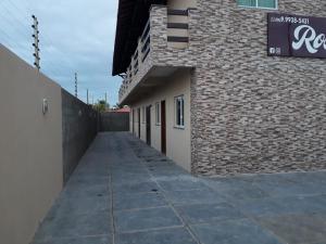 a building with a sidewalk next to a brick wall at POUSADA ROSA MAR in Luis Correia