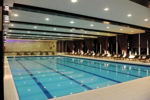 Una gran piscina con sillas en un edificio. en Alpin Resort Hotel - Apartamentele 2403-2404- proprietate administrata de gazda privata, en Poiana Brasov 6 fotos más