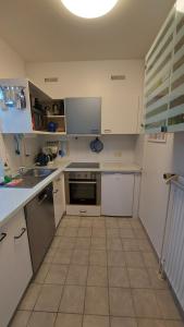 eine Küche mit weißen Geräten und Fliesenboden in der Unterkunft Haus Nika in Carolinensiel in Carolinensiel
