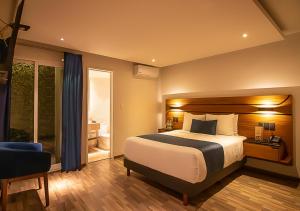 a hotel room with a bed and a chair at Hotel Boutique Maria in Morelia